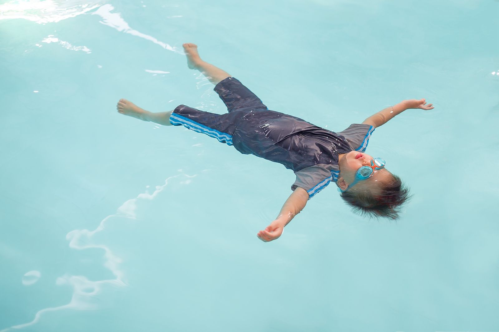 Young boy floating in a swimming pool